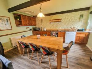 cocina con mesa de madera y sillas en Wetheral Cottages Package 1, en Great Salkeld