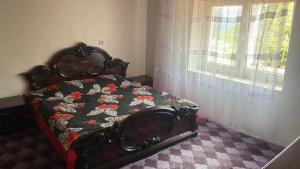 a bedroom with a bed with a floral comforter and a window at Guest House BOZVILL in Bozovec