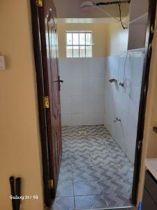 a bathroom with a shower and a door with a tile floor at Upperhill suites in Kisii
