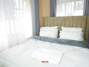 a bed with white sheets and pillows in a bedroom at Upperhill suites in Kisii