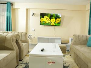 a living room with a couch and a tv on the wall at Upperhill suites in Kisii