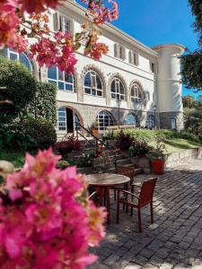 a table and chairs in front of a building with pink flowers at Hotel Casacurta in Garibaldi