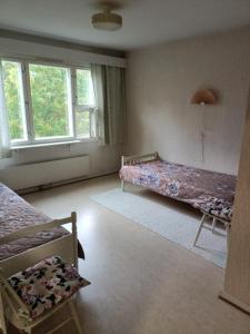 a bedroom with two beds and two windows at Siisti valoisa kolmio in Lieksa