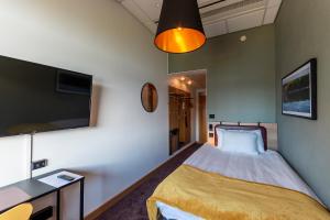 um quarto com uma cama e uma televisão de ecrã plano em Skåvsjöholm Hotell och Möten em Akersberga