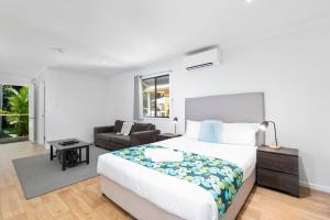 a white bedroom with a bed and a couch at Mossman Resort Holiday Villas in Mossman