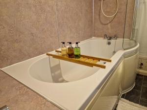 a bath tub with a shelf in it with bottles on it at Wetheral Cottages Package 1 in Great Salkeld