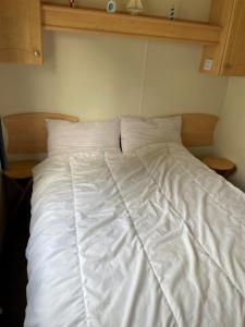 a bed with a white comforter on top of it at 6 Berth Caravan For Hire In Hunstanton At Manor Park Holiday Park Ref 23004a in Hunstanton