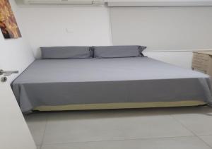 Cama en habitación blanca con colcha gris en Apartamento Olof, en Río de Janeiro
