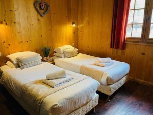 two twin beds in a room with wooden walls at Chalet Les Lanchettes in Morzine