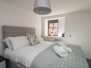 a bedroom with a bed with white sheets and pillows at Llety Pen Deitsh 2 in Caernarfon