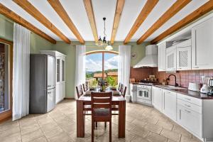 a kitchen with white cabinets and a table with chairs at Villa Dol an ideal spa and wellness escape in Istria in Buzet