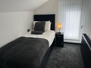 Schlafzimmer mit einem Bett mit einem schwarzen Kopfteil und einer Lampe in der Unterkunft OYO The Avenue in Scunthorpe