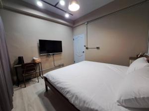 Schlafzimmer mit einem weißen Bett und einem Flachbild-TV in der Unterkunft 敘時光行旅 Telling Story House in Sanxing Township