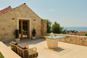 eine Terrasse mit einem Tisch und Stühlen sowie ein Steingebäude in der Unterkunft Palace Natali in Dubrovnik