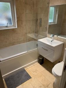 a bathroom with a tub and a sink and a toilet at Super 1 bedroom in a stunning apartment with shared kitchen and living room - 2C The Charteris in London