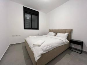 a bed with white sheets and a window in a room at Menahem Arber 4 Bedroom in Tel Aviv