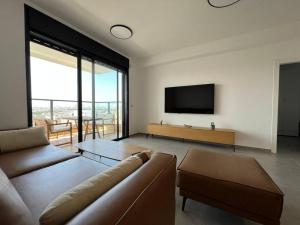 a living room with a couch and a flat screen tv at Menahem Arber 4 Bedroom in Tel Aviv