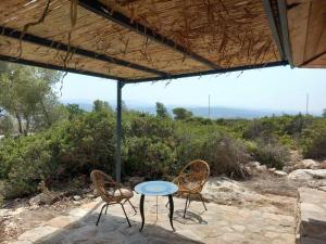 uma mesa e duas cadeiras sentadas sob um guarda-sol em בית בהר- בקתה יפיפיה בקצה הגלבוע em Sede Terumot