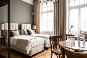 2 Betten in einem Hotelzimmer mit einem Tisch und einem Esszimmer in der Unterkunft Avanti Palazzo in Krakau