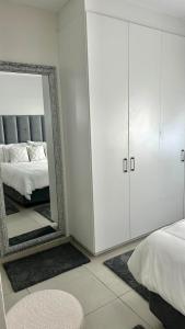 ein weißes Schlafzimmer mit einem Spiegel und einem Bett in der Unterkunft APOLLO LUXURY APARTMENT in Sandton