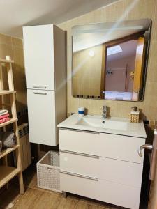 W łazience znajduje się biała umywalka i lustro. w obiekcie Ático a 8 minutos de Toledo y 15 del Puy Du Fou w mieście Bargas