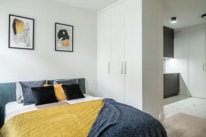 a white bedroom with a bed with a yellow blanket at Apartments City Center Wroclaw in Wrocław