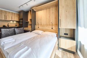 a bedroom with a large white bed and wooden cabinets at Appartement Bittner in Saalbach-Hinterglemm