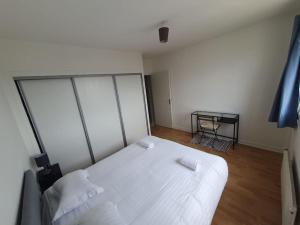 a bedroom with a white bed and a table at Le Drapeau : Apt 2 Personnes, 1 ch, avec Balcon in Dijon