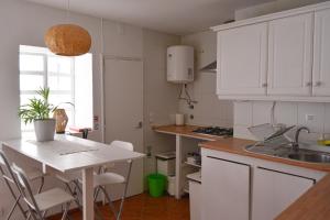 une cuisine avec des placards blancs et une table avec des chaises dans l'établissement SHARED APARTMENT WITH BRIGHT PRIVATE PATIO IN LISBOA, à Lisbonne