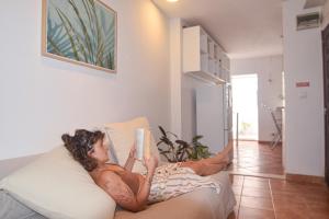 une femme qui lit un livre sur un canapé dans l'établissement SHARED APARTMENT WITH BRIGHT PRIVATE PATIO IN LISBOA, à Lisbonne