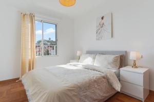 Habitación blanca con cama y ventana en Camara de Lobos Apt by HR Madeira, en Câmara de Lobos