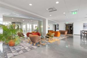 a lobby with chairs and plants on a tiled floor at Best Western Plus Sthlm Bromma in Stockholm