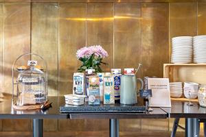 a table with coffee and milk and a vase of flowers at Best Western Plus Sthlm Bromma in Stockholm