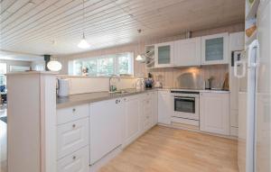 HelberskovにあるBeautiful Home In Hadsund With 3 Bedrooms And Wifiの白いキャビネットと木製の天井が備わるキッチン