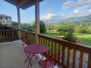 uma mesa roxa e cadeiras num alpendre com vista em Gîte - La Maldina em Oriol-en-Royans