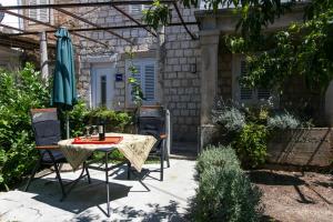 un patio con mesa, sillas y sombrilla en Apartment Ana en Dubrovnik