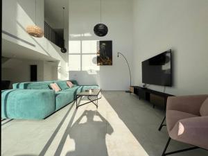 a living room with a blue couch and a tv at Menahem Arber Pool 5 Bedroom in Tel Aviv