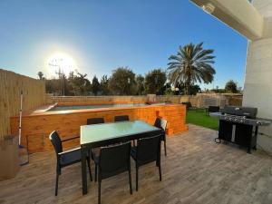 eine Terrasse mit einem Tisch, Stühlen und einem Grill in der Unterkunft Menahem Arber Pool 5 Bedroom in Tel Aviv