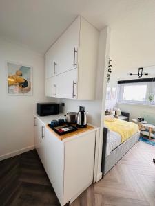 Private Room in Modern Shared Apartment, Each with Kitchenette, Central Birmingham في برمنغهام: مطبخ مع دواليب بيضاء وسرير في الغرفة