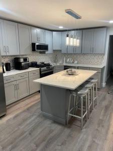a kitchen with white cabinets and a island with bar stools at Shirley Air in Boston