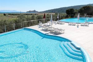 a large swimming pool with chairs and umbrellas at Gitavillage Talamone in Talamone