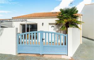 a blue gate in front of a house with a palm tree at Nice Home In La Faute Sur Mer With 3 Bedrooms And Wifi in La Faute-sur-Mer