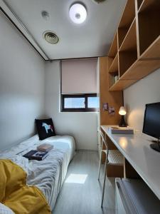 a small bedroom with a bed and a desk at Coem Livingtel in Goyang