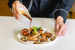a person pouring sauce on a plate of food at Westotel Nantes Atlantique in La Chapelle-sur-Erdre