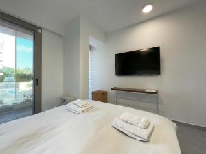 um quarto com uma cama branca e toalhas em Luxury Apartment Port of Jaffa em Tel Aviv