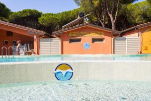 a swimming pool with a sign on the side of a house at Gitavillage Il Gabbiano in Albinia