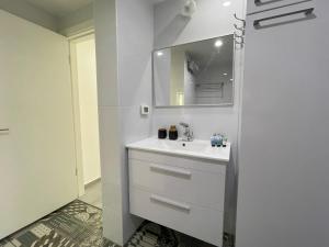 La salle de bains blanche est pourvue d'un lavabo et d'un miroir. dans l'établissement Luxury Apartment Port of Jaffa, à Tel Aviv