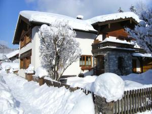 a house covered in snow next to a fence at Ferienwohnung Kaidisch - Reiter in Ruhpolding