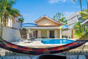 a hammock in front of a house with a pool at Maravilhosa casa no Cond. fechado Morada da Praia in Boracéia