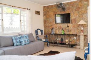 a living room with a couch and a stone wall at Maravilhosa casa no Cond. fechado Morada da Praia in Boracéia